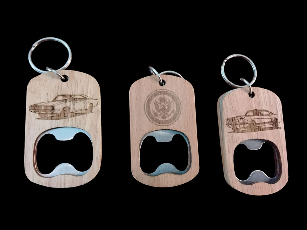 Three wooden keychain bottle openers with engraved car designs and a logo.